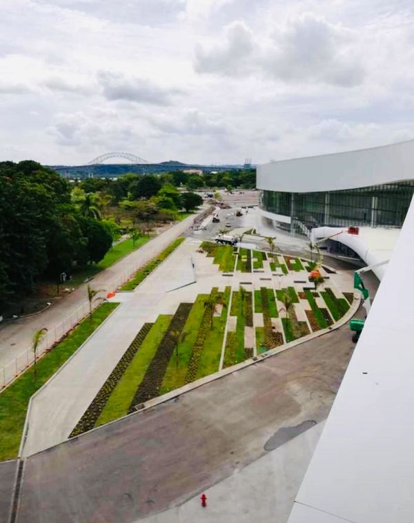 Modern building with landscaped garden and paved pathways under a cloudy sky.