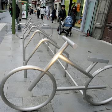Metal bike-shaped bike racks on a city sidewalk. bancas de acero inoxidable
papeleras
paradas
