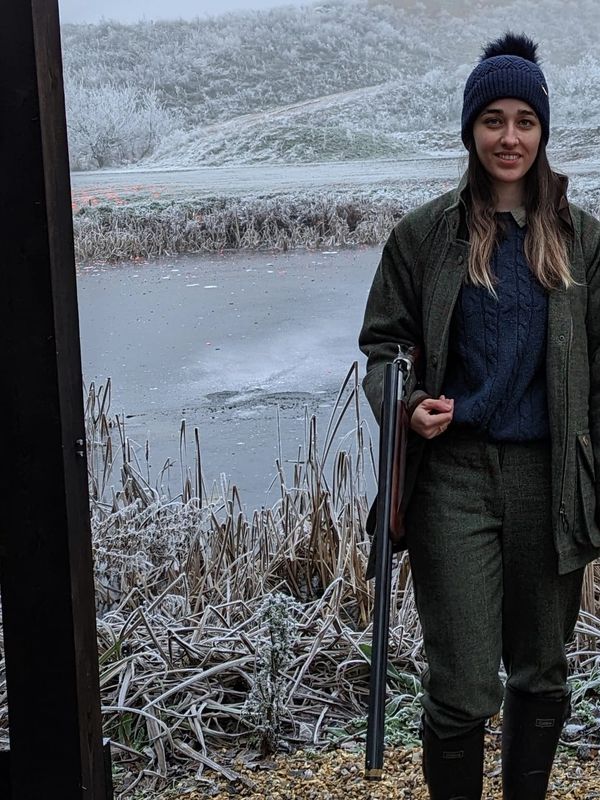 Woman in winter clothes smiling in a snowy landscape.