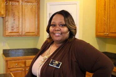Smiling woman with name tag standing in a kitchen.