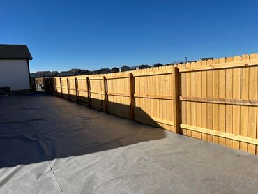 Newly installed wooden fence under a clear blue sky.