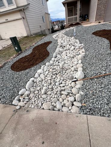 Landscaped front yard with decorative rocks and mulch beds.