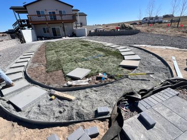 Backyard landscaping with fresh sod and stone pathway under construction.