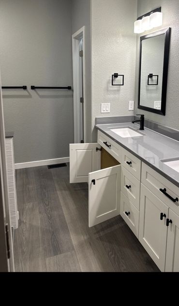 Modern bathroom with double sinks, white cabinets, and gray flooring.