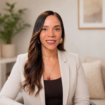 Confident woman in a beige blazer smiling warmly indoors.