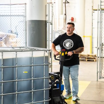 Man operating pallet jack in warehouse.
