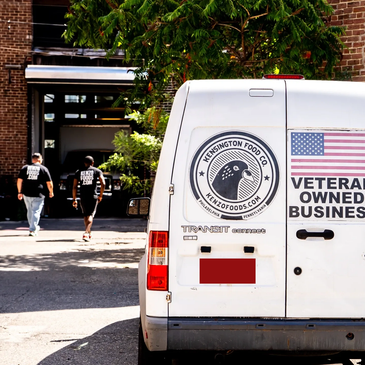Veteran-owned Kensington Food Co. van parked outside with two people in background.