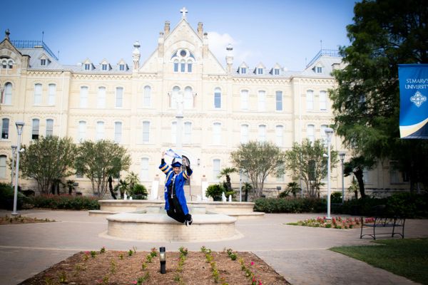 Graduates celebrating outside a historic university building on a sunny day.