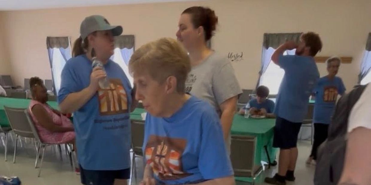 People gathered indoors, some wearing matching blue shirts with a logo.
