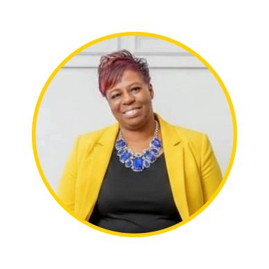 Smiling woman in yellow blazer and bold blue necklace.