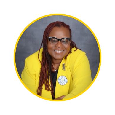 Smiling woman with glasses wearing a bright yellow blazer and long red dreadlocks.