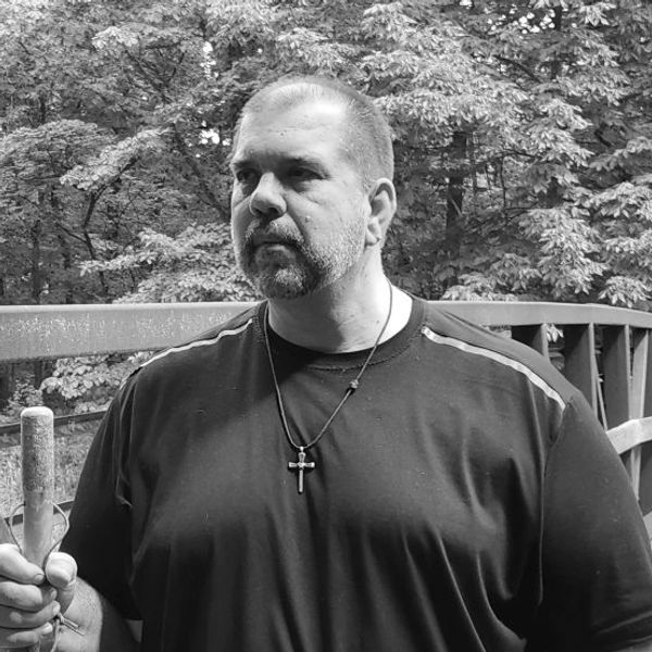 Coach Dennis Wagner standing on a wooden bridge with a walking stick,