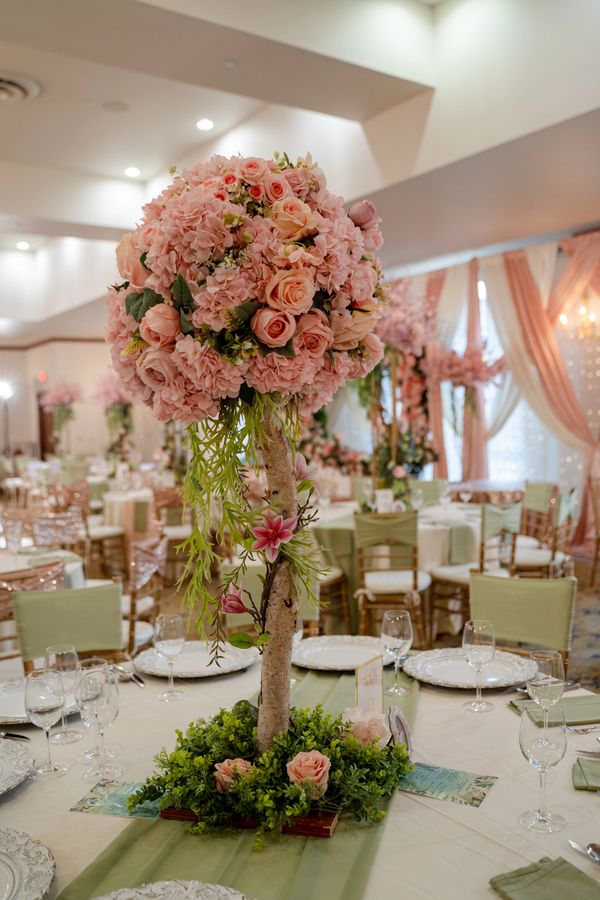 Elegant pink floral centerpiece on a wedding table with green accents.