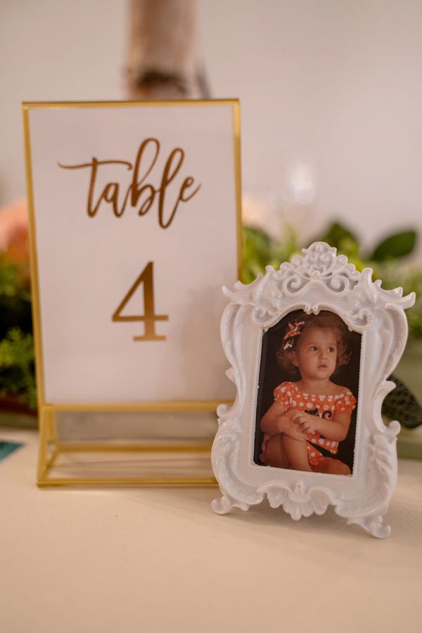 A table number 4 card next to a framed photo of a young child in an ornate white frame.