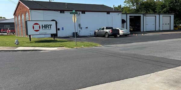 Building with HRT sign and parked cars on a sunny day.