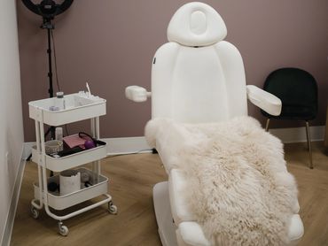 A modern beauty treatment room with a white chair and ring light.