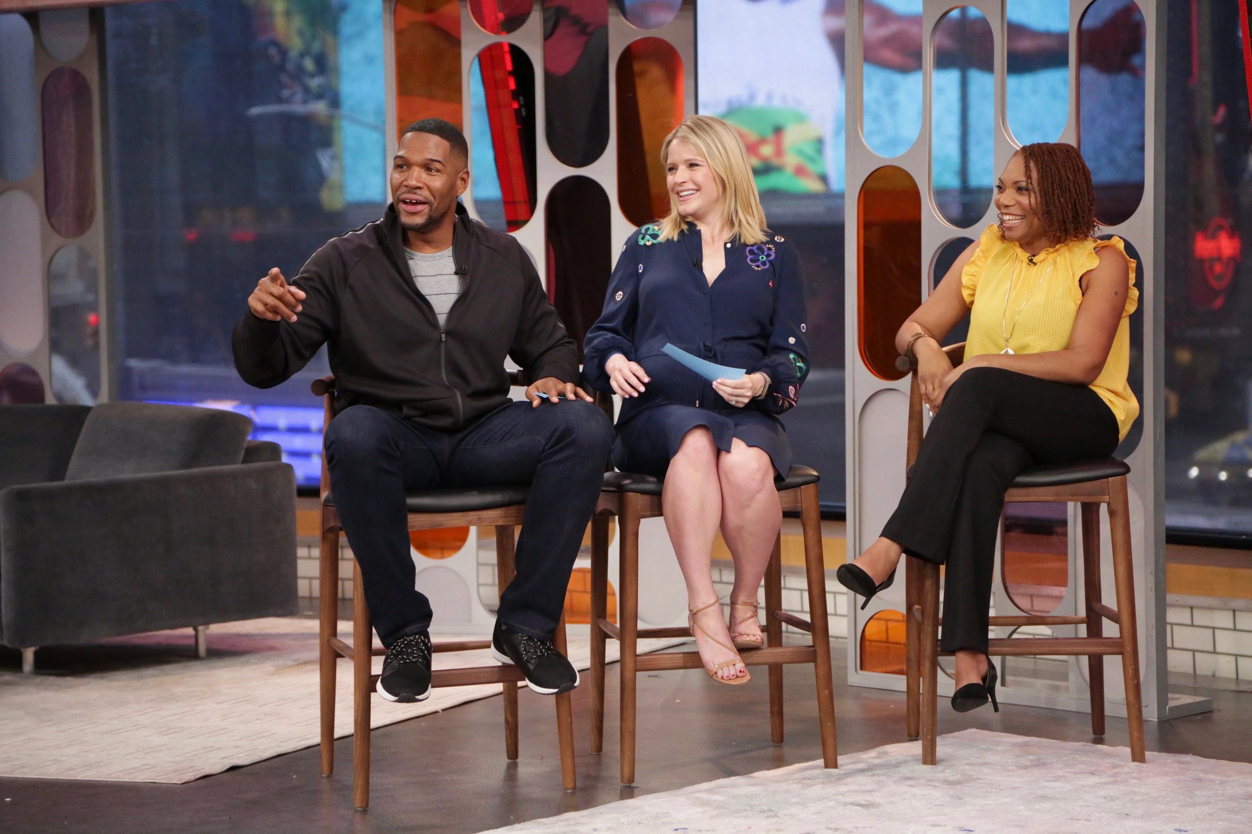 Three people sitting and talking on a TV show set.