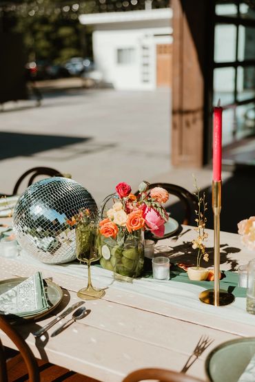 Photo of reception table with brightly colored decor and disco ball. Photo: The Wickerts Photography