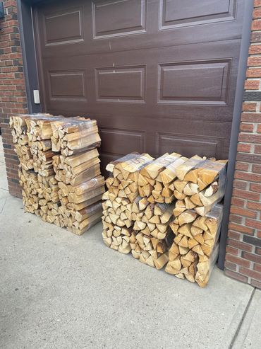 Stacks of firewood neatly arranged against a brown garage door.