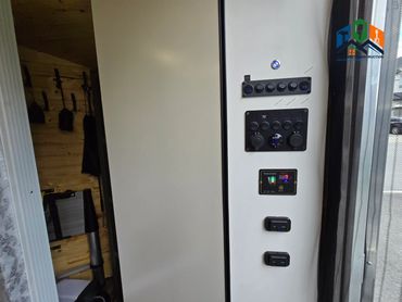Pine Box control panel with light switches, inverter switch & electrical setup inside camper
