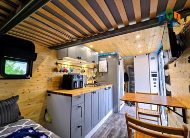 Interior shot from sleeping area showing table, kitchenette & tankless water heater system