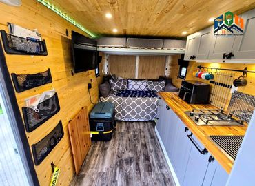 Pine Box camper interior with kitchenette, folding table, bed, fridge, TV & net storage