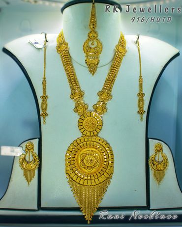 Intricate gold Rani necklace set displayed on a white mannequin.