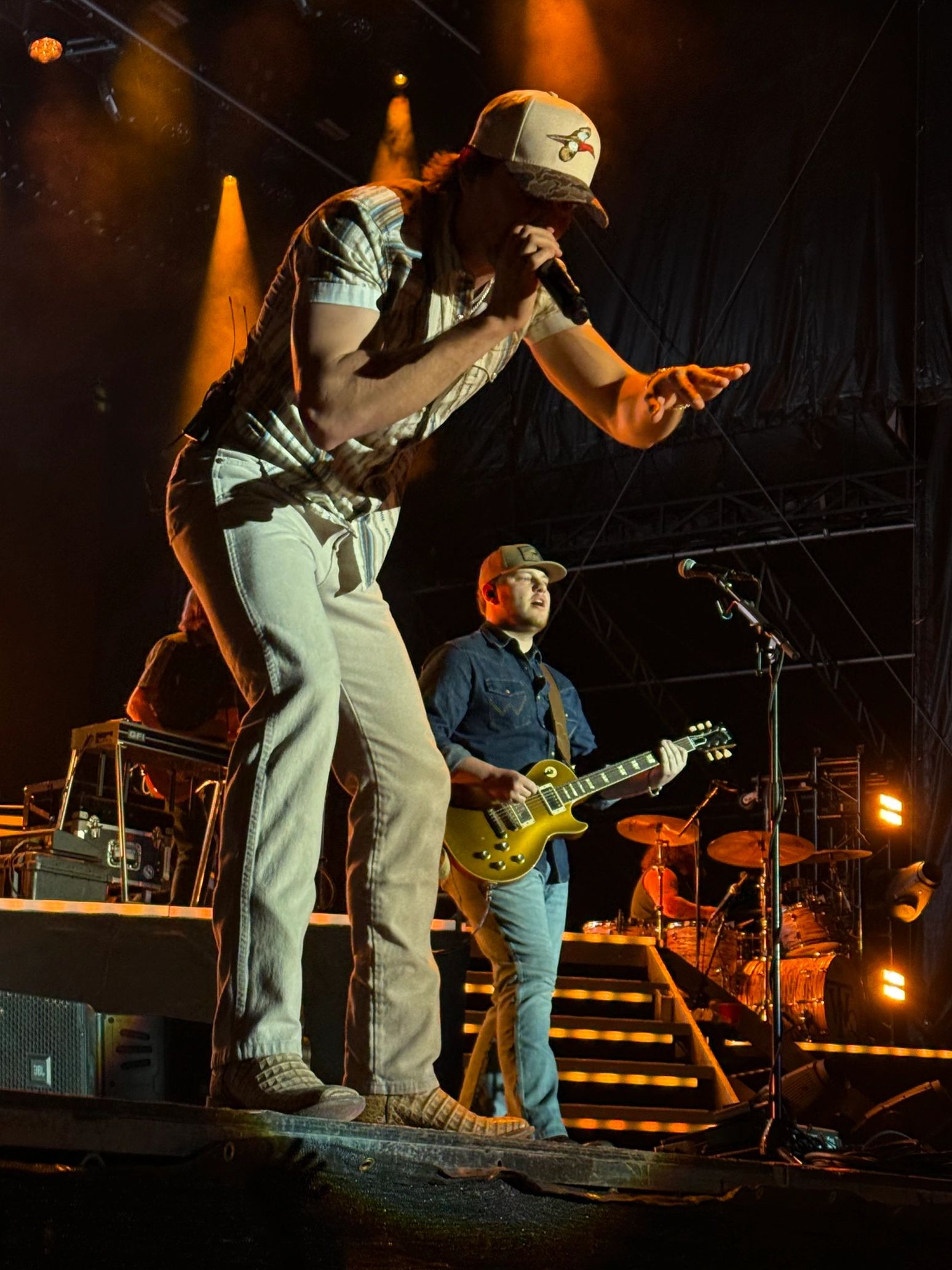 Lead singer and guitarist performing on stage with dramatic lighting.