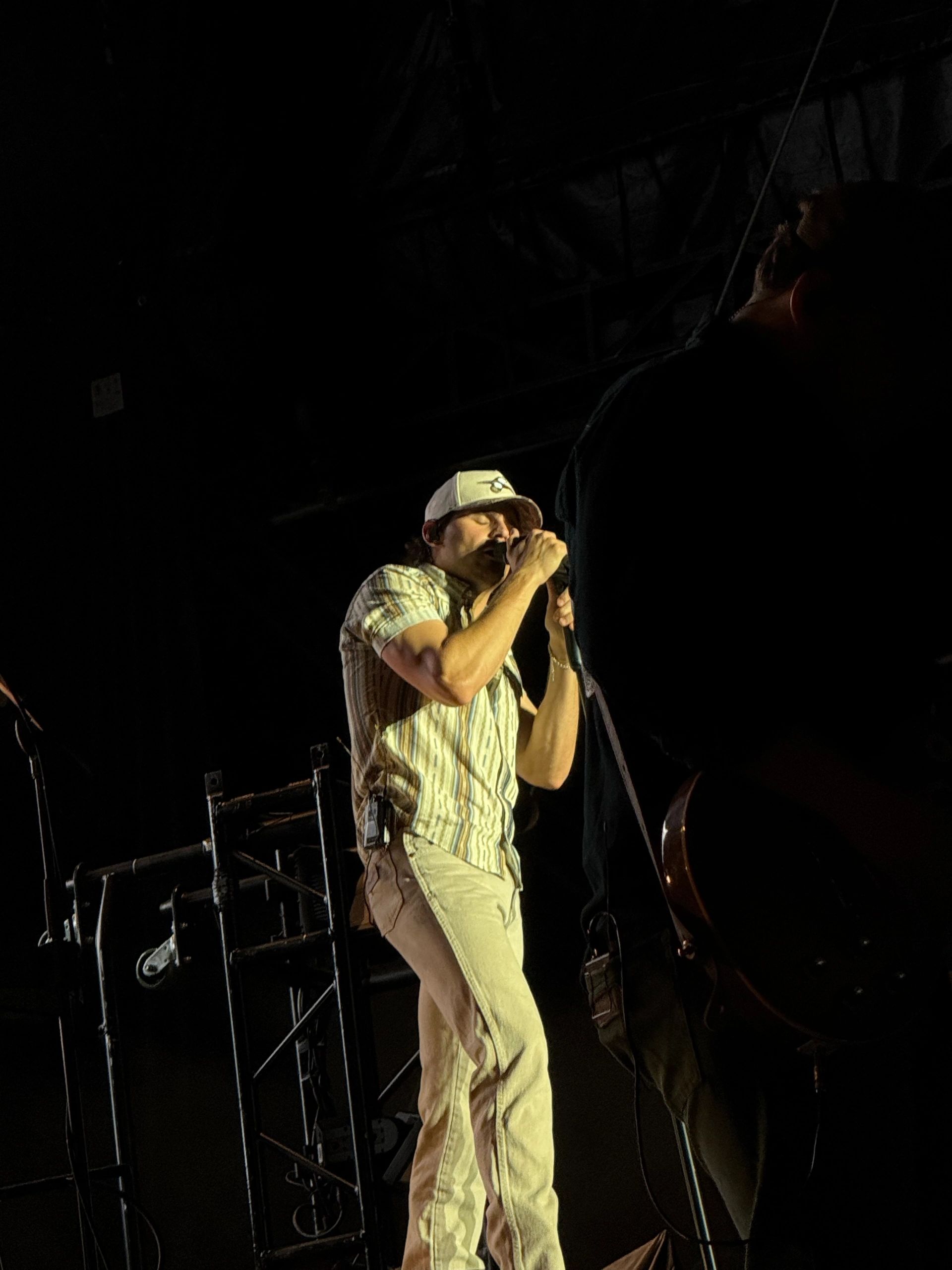 Singer passionately performing on stage under spotlight.