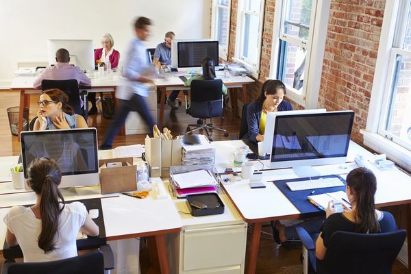 Employees collaborating in a modern open-plan office space with desks and computers