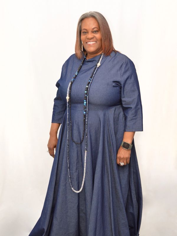 Woman in a blue dress with a long necklace and smartwatch.