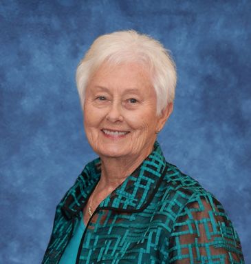 Smiling elderly woman with white hair against a blue backdrop.