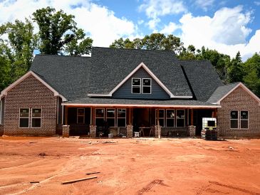 Newly built large brick house with dark roof under a blue sky.