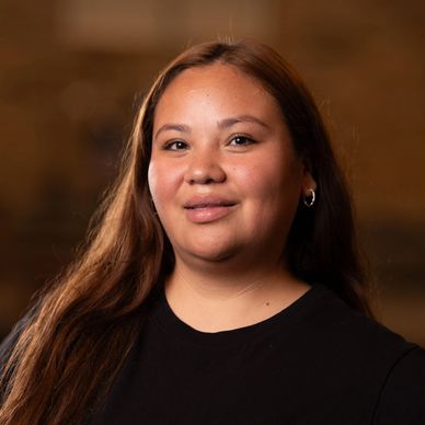 Portrait of a smiling woman with long brown hair and hoop earrings.