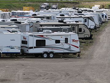 Multiple parked travel trailers in a storage lot.