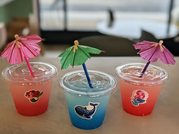 Three colorful drinks with paper umbrellas and ocean-themed stickers.