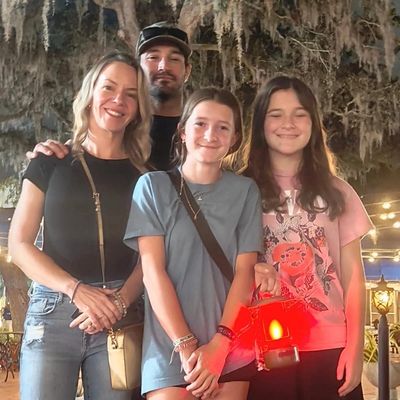 A happy family of four posing under hanging moss with warm lighting.