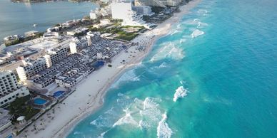 Aerial view of a beachfront city with turquoise waves and sandy beach.