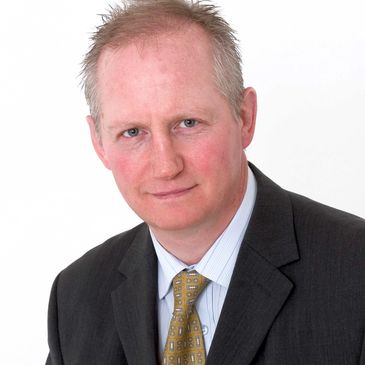 Professional man in suit and patterned tie against white background.