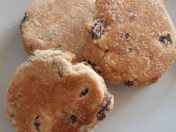 Three welsh cakes on a plate. Welsh cakes are a traditional Welsh treat. These homemade welsh cakes are stuffed with currants and dusted with sugar. 