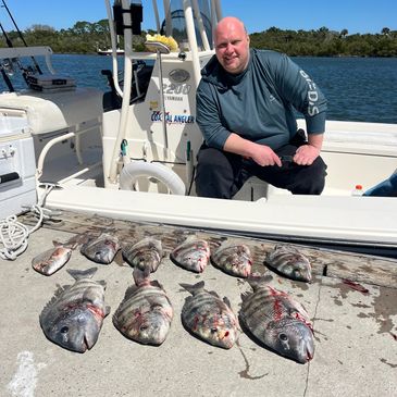 Man proudly posing with his fresh catch of fish by a boat.