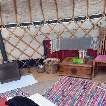 Comfortable yurt interior with bed, seating area and soft lighting at Sunny Hill Campsite