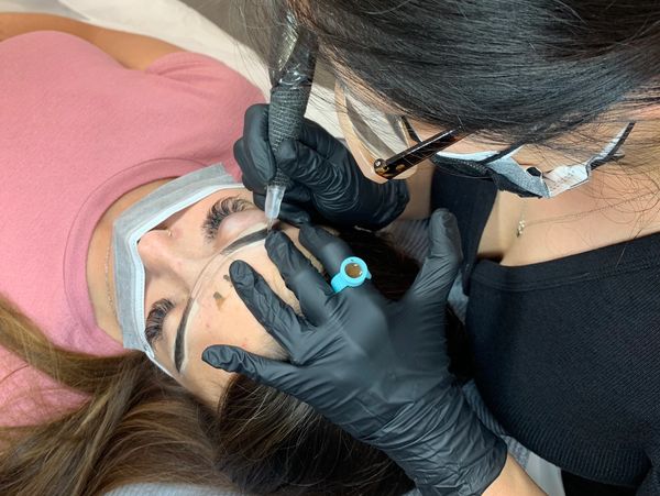 Student performing eyebrow tattoo procedure