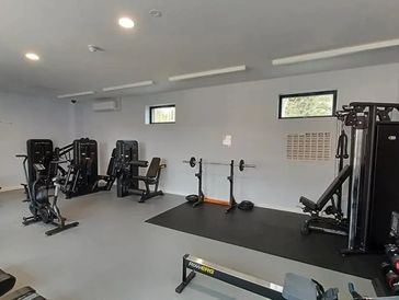 A clean, well-equipped gym with weight machines and dumbbells.