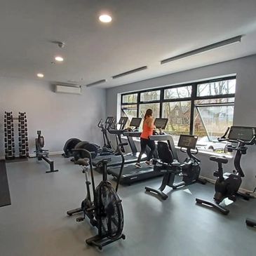 A person exercising on a treadmill in a modern gym with various fitness equipment.