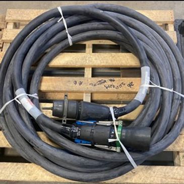 Coiled heavy-duty electrical cable with connectors on a wooden pallet.