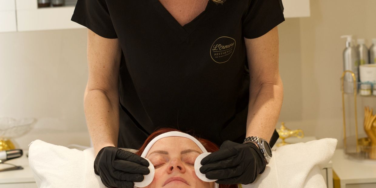 Aesthetician performing facial treatment on a woman.