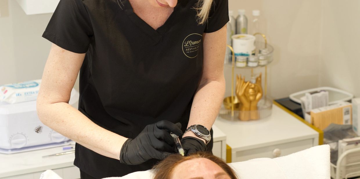 Aesthetician injecting a treatment into a client's forehead.