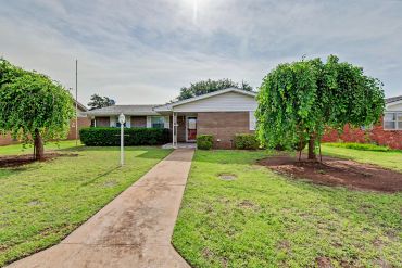Front exterior of brick home with landscaped lawn and driveway - real estate photo, Sayre, OK