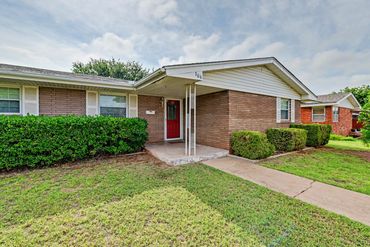Front porch entrance of brick ranch home with red door - real estate photo, Sayre, OK